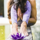 Praying woman sitting behind a purple glass lotus on a tree trunk over the water. - PhotoDune Item for Sale