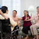 Close-up of senior woman in wheelchair with her caregiver in background and elderly friends - PhotoDune Item for Sale