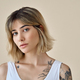 Cool blonde gen z girl pretty face and tattoos at beige background. Portrait. - PhotoDune Item for Sale