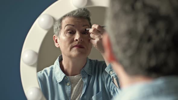Senior Woman Doing Makeup in Front of Mirror