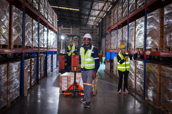 Warehouse workers under working factory cargo hand pulling pallet truck ...