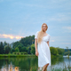 Portrait of a cute girl in a white dress on the river bank during sunset - PhotoDune Item for Sale