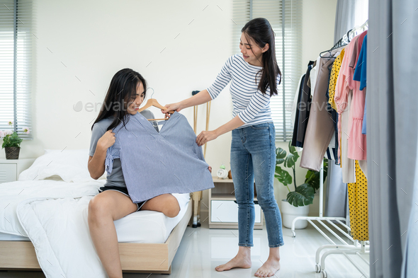 Asian young amputee leg woman and friend choosing clothes on closet rack.