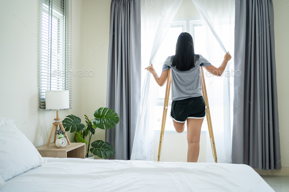 Asian young amputee leg woman wake up and stretching body in morning.