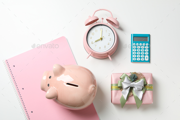 Piggy bank, watch, calculator and gift box on white background, top view
