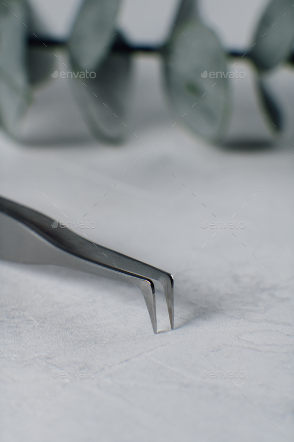 Close up of tip of tweezers for separating fake lashes throughout procedure, lying on table