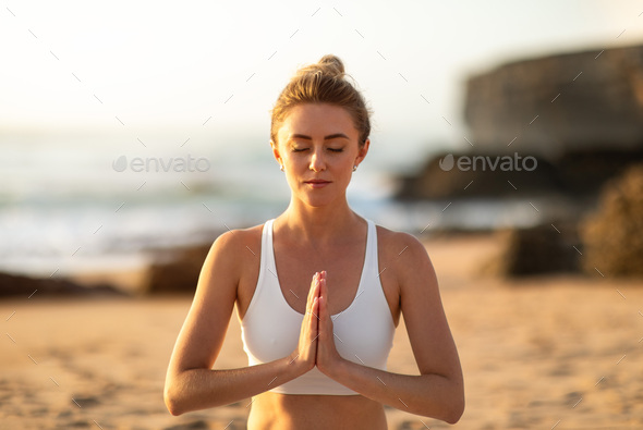 Calm slim woman practicing yoga and meditating, enjoying training on beach  near sea, exercising Stock Photo by Prostock-studio