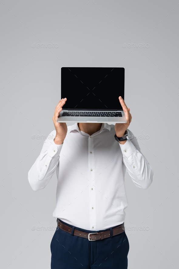 hispanic manager in white shirt obscuring face with laptop isolated on grey
