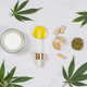 Cosmetic jar, pipette with CBD oil, capsules and tea near green cannabis leaves. Mockup - PhotoDune Item for Sale
