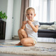 Little blonde girl sits at home on the carpet and collects puzzles - PhotoDune Item for Sale
