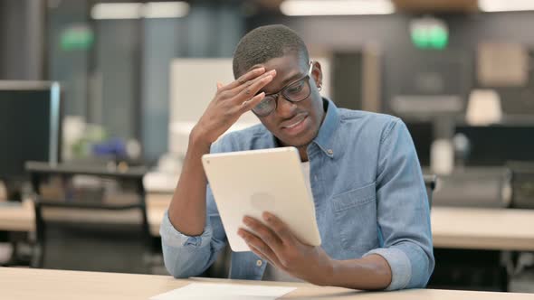 Young African American Man Having Loss on Tablet in Office alt