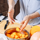 Senior Caucasian woman putting chopped pumpkin pieces into a bowl - PhotoDune Item for Sale