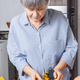 Caucasian senior woman with gray hair grates pumpkin to make homemade pumpkin pie - PhotoDune Item for Sale