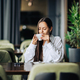A young woman is sitting in a coffee shop and sipping fresh coffee. - PhotoDune Item for Sale