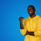 Cheerful handsome young black guy pointing finger at empty space, isolated on blue background - PhotoDune Item for Sale