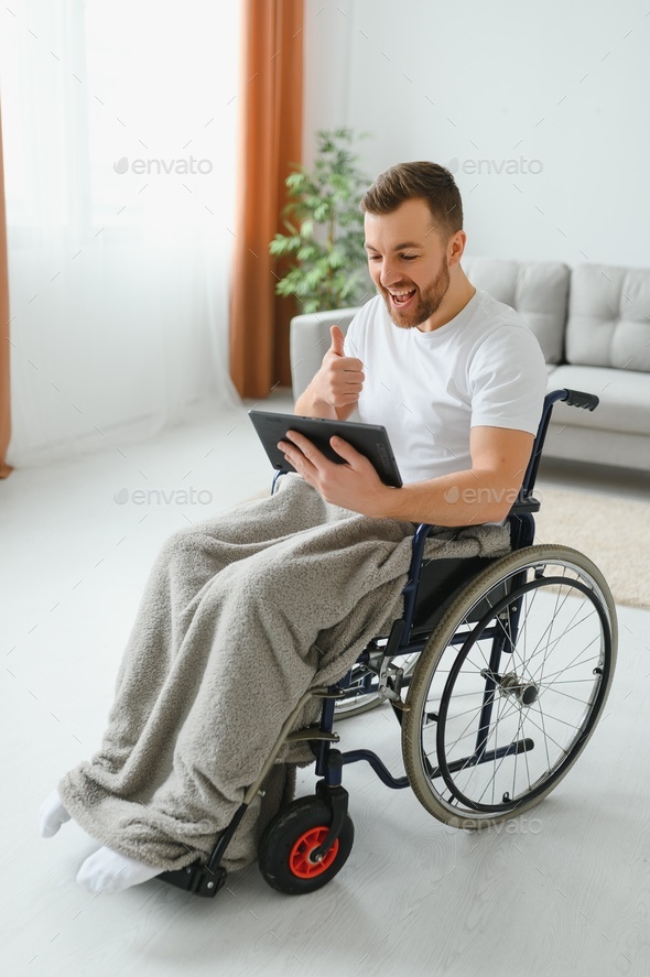 Modern young disabled man in wheelchair having video call Stock Photo