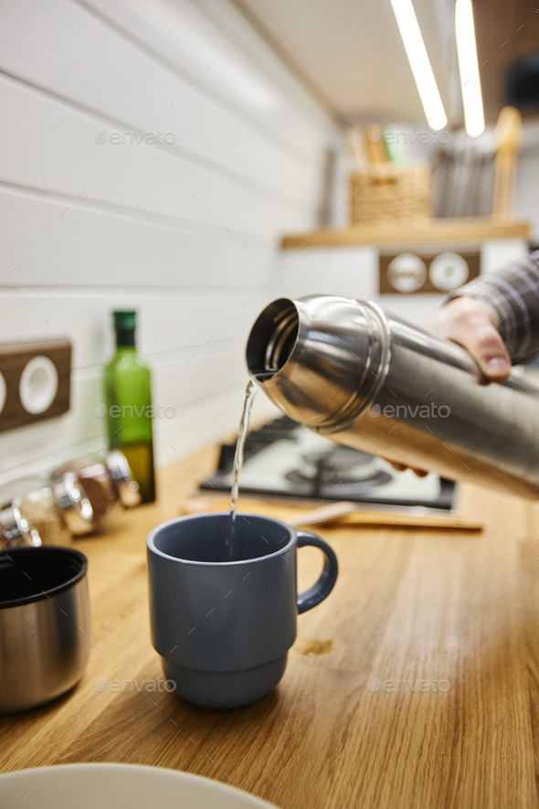 Pouring hot tea from a thermos into a cup in the mountains. Stock