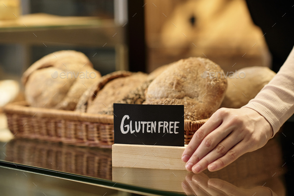 Fresh breads in artisan bakery with female hand holding gluten free sign