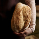 Close up of young woman with fresh loaf of golden bread in artisan bakery - PhotoDune Item for Sale