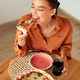 Excited woman enjoying eating tasty pizza, holding and biting slice, sitting at table in kitchen - PhotoDune Item for Sale