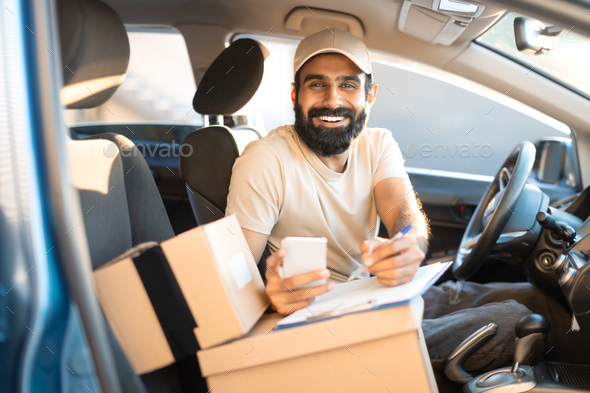 Indian Courier Taking Notes Using Application On Phone In Automobile - Stock Photo - Images