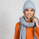 Cheerful woman in scarf and warm sweater near white brick wall - PhotoDune Item for Sale