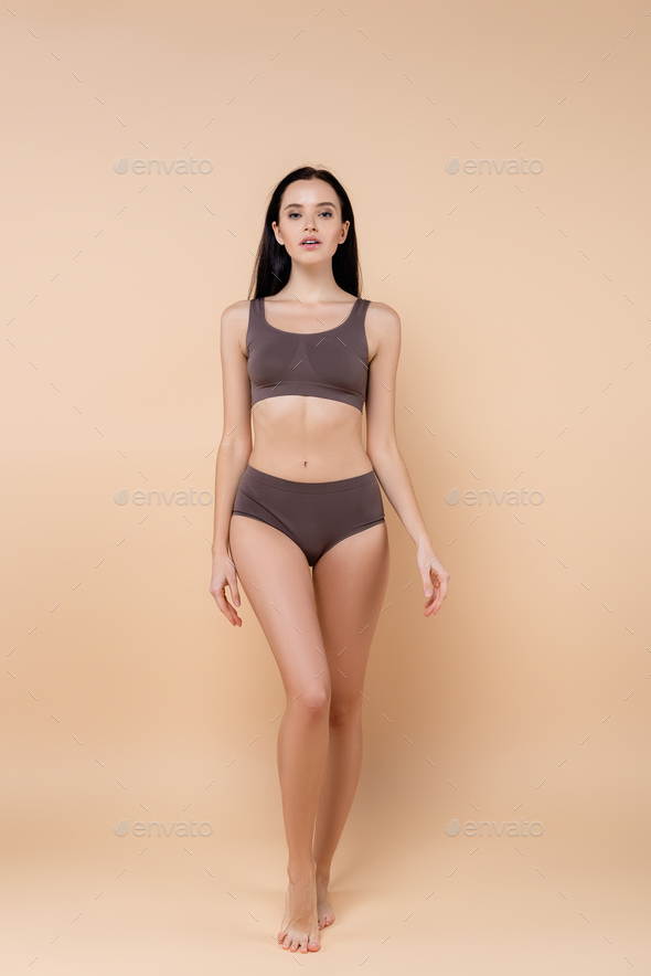 full length view of young woman in underwear standing on beige Stock Photo  by LightFieldStudios