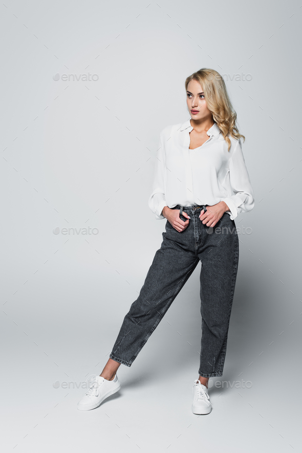 Man pose in studio with hands in pockets while woman is resting - Stock  Image - Everypixel