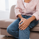 cropped view of african american woman suffering from knee pain while sitting on couch - PhotoDune Item for Sale