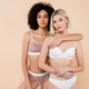 african american woman hugging blonde friend while posing isolated on beige - PhotoDune Item for Sale