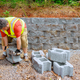 As construction worker lifted concrete block, to ensure its proper placement on the retaining wall. - PhotoDune Item for Sale