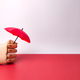 Wooden hand holding red umbrella on a red and white background with copy space. - PhotoDune Item for Sale