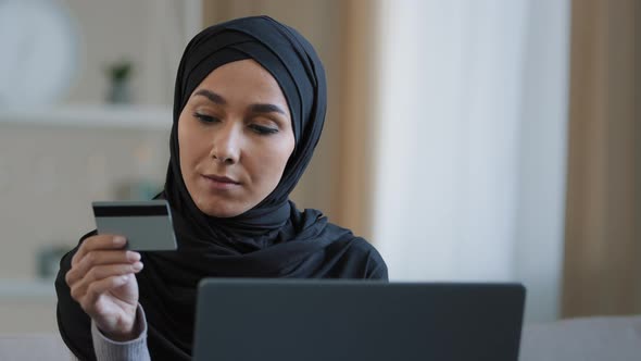 Attractive Girl in Hijab Holding Credit Card Pay Online Order Use Banking Application on Laptop alt
