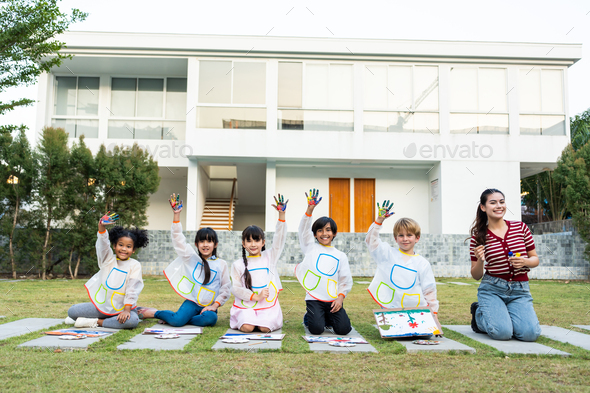 Portrait group of young student paint board outdoors in school garden.