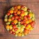 from above: a round plate full of colourful cherry and small plum tomatoes on wooden background - PhotoDune Item for Sale