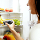 Woman hand taking or picks up box of blueberry out of open refrigerator, fridge - PhotoDune Item for Sale