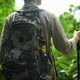Rear view of man tourist with backpack and trekking sticks on a hiking trip in forest. - PhotoDune Item for Sale