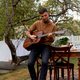 young man sits at the table and plays the guitar - PhotoDune Item for Sale
