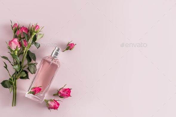 A chic bottle of cosmetic spray, perfume for women on a delicate background among small rosebuds.