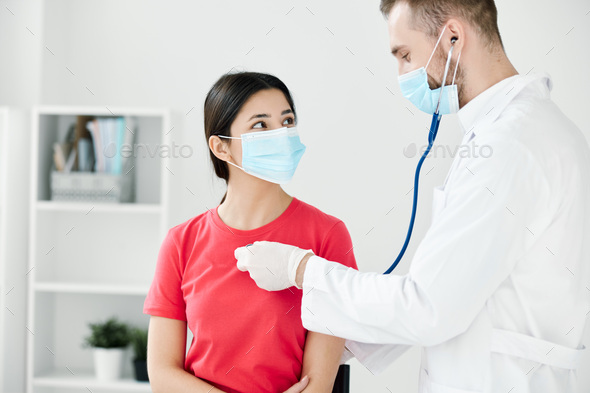 doctor in a medical mask and a dressing gown examine a woman in a