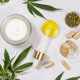 Cosmetic jar, pipette with CBD oil, capsules and tea near green cannabis leaves. Mockup - PhotoDune Item for Sale