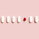 Mix of medical pills with one red capsule in a line on light pink top view. Dietary supplements - PhotoDune Item for Sale