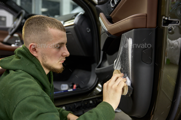 Car detailing process, closeup male worker cleaning door with