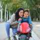 Happy Latin mother hugging her son on a balance bike in a park. - PhotoDune Item for Sale