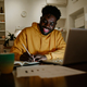 A happy african american remote worker is sitting at home late at night - PhotoDune Item for Sale