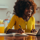 A cheerful african american female freelancer is writing down notes and tasks - PhotoDune Item for Sale