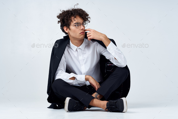 handsome guy in trousers shirt and jacket and sneakers In a bright room and curly hair