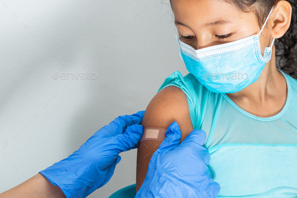 Doctor putting an adhesive bandage on a girl\'s arm after hurting her skin or injecting vaccine
