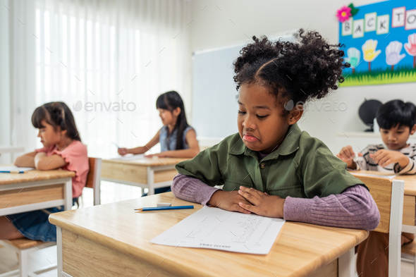 African American student doing exam in classroom at elementary school ...