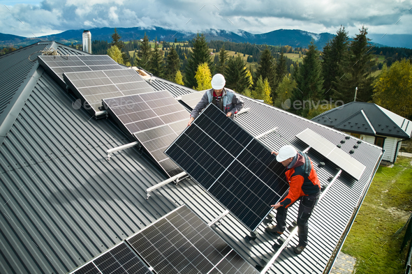 Workers installing solar panels on a roof of house Stock Photo by ...